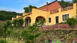A yellow building with arched windows and a stone wall. - Agriturismo LaValleggia (Tovo San Giacomo)