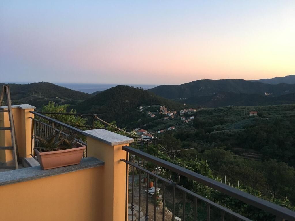 Un balcon donnant sur un paysage vallonné et parsemé de bâtiments.