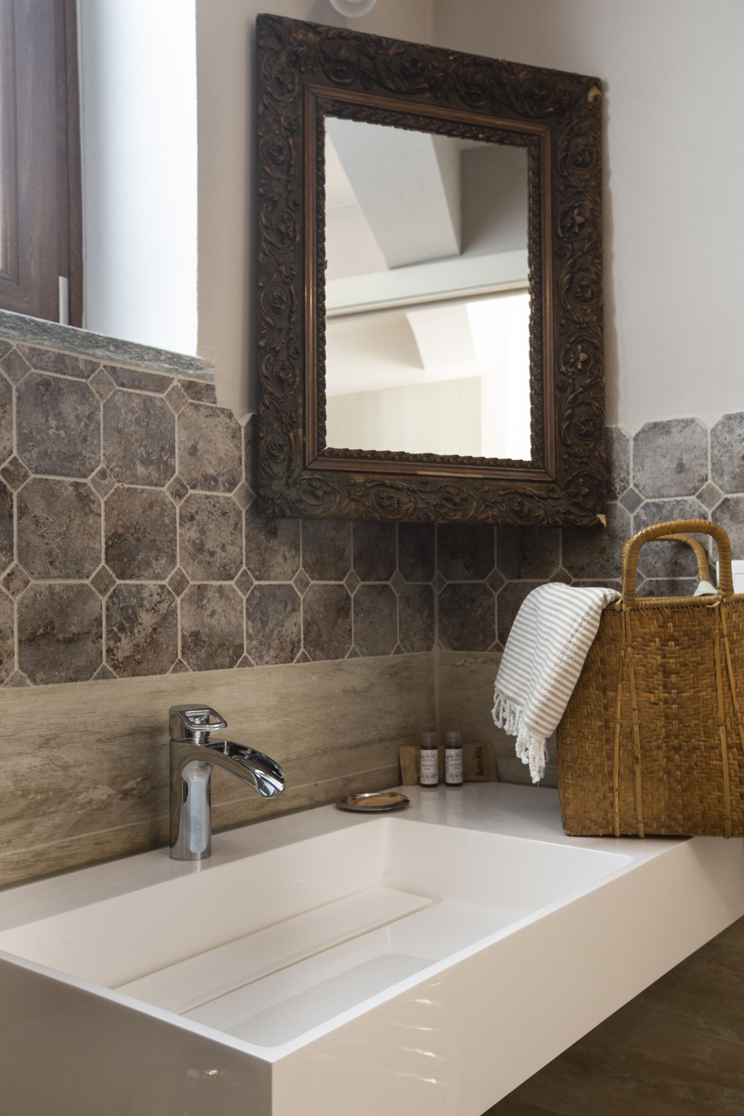 A bathroom with a white sink, a decorative mirror, and a woven basket.