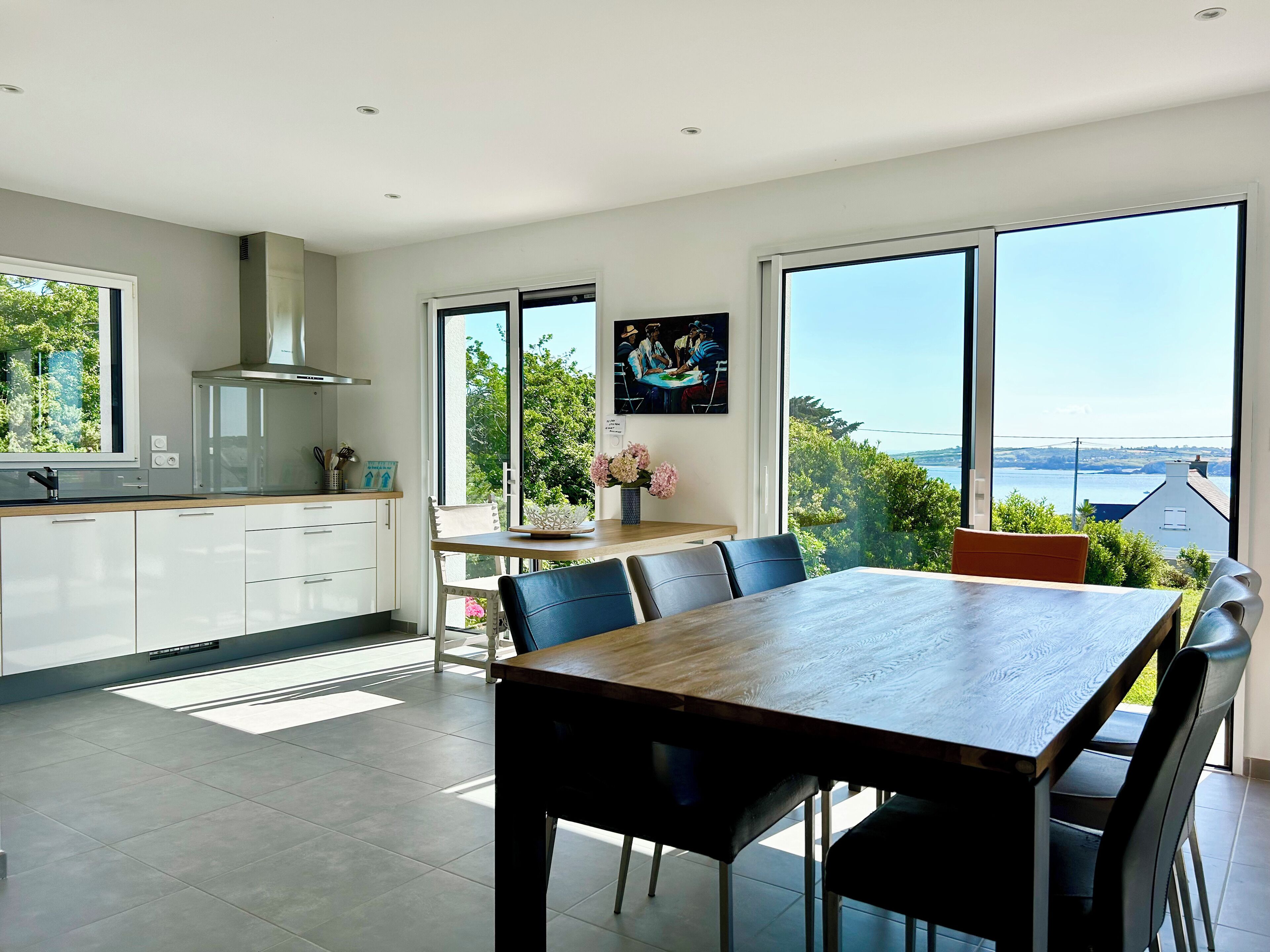 A modern kitchen with white cabinets and a large window overlooking a scenic view.