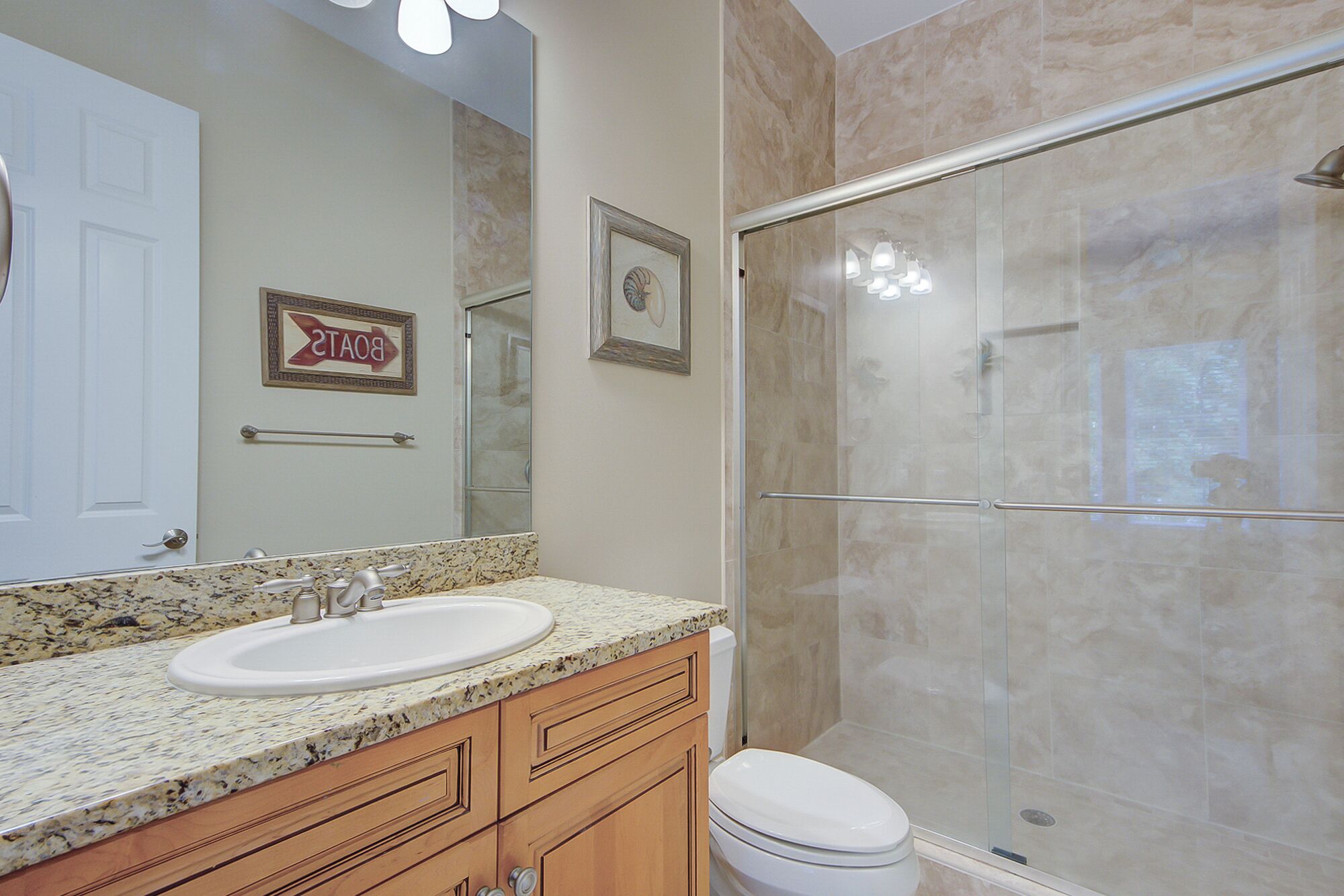Une salle de bain avec un double vasque, des meubles en bois, des toilettes et une douche à parois de verre.
