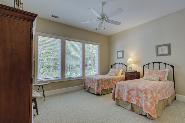 A bedroom with two beds, a ceiling fan, and a window with blinds.