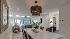 A modern dining area with a large table, chairs, a chandelier, and a view of the living room. - 4th Row from the beach! 2 Bed/2 Bath Townhouse (Hilton Head Island)