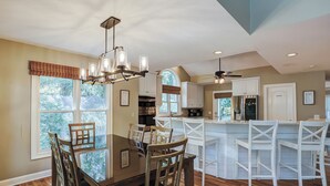 Una cocina amplia con zona de comedor, que cuenta con una araña, sillas de madera y vistas al exterior.