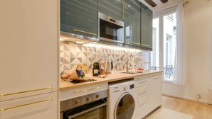 A modern kitchen with a built-in oven, microwave, and washing machine. - Sweett | Clery - Two Bedroom Apartment, Sleeps 4 (Paris)
