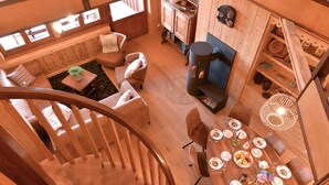 Un interior de madera con comedor, chimenea y escalera.