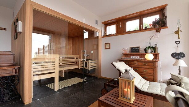 Una habitación moderna con un banco de madera, una mesita con una vela y un aparador con adornos.