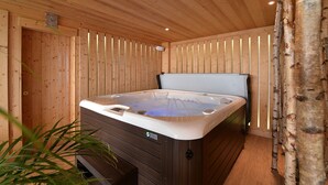 Una habitación de madera con jacuzzi, paredes de madera y techo con vigas de madera.