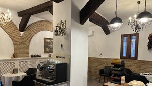 Un restaurante con máquina de café Nespresso, vigas de madera y una araña.