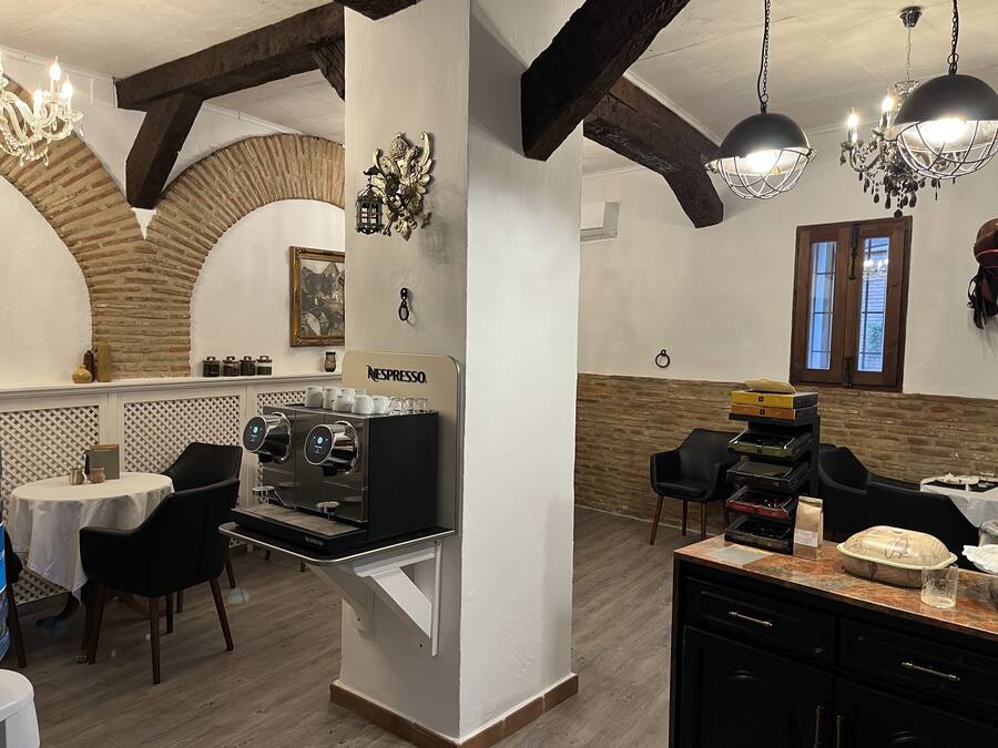 A restaurant with a Nespresso coffee machine, wooden beams, and a chandelier.