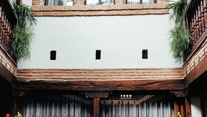 Un edificio con una escalera central, balaustradas de madera y ventanas en arco.