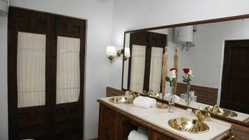 A bathroom with a wooden vanity, a large mirror, and a gold sink.