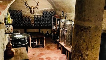 Interior con techo abovedado, columna de piedra y mesa de madera con una botella.