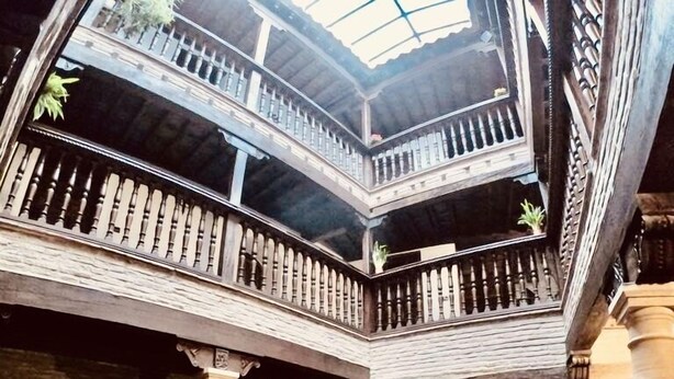 Un amplio atrio con una zona de estar central, una escalera y un alto techo con tragaluces.
