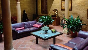 Un amplio patio con techo alto, sofás de cuero, una mesa de centro y plantas en macetas.