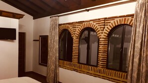 Un dormitorio con cama, una ventana enmarcada en piedra decorativa y una puerta.