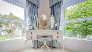 A white vanity with a bench, two mirrors, and a vase with flowers. - Altahammond House (Carrickfergus)