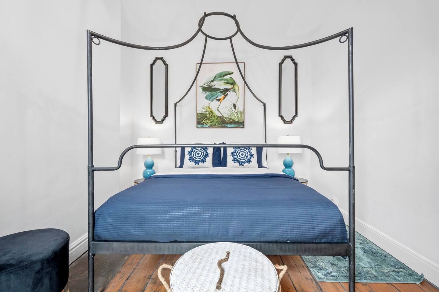 A bed with a metal frame, blue bedding, and decorative pillows.