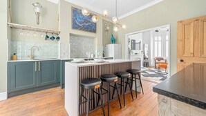 A modern kitchen with a central island, bar stools, and a hanging light fixture. - This house is a 4 bedroom(s), 3 bathrooms, located in Manchester, England. (Manchester)