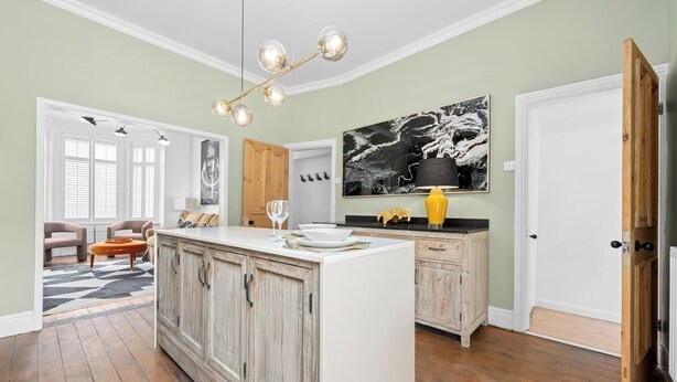 A kitchen with a central island, wooden cabinets, and a modern pendant light. - This house is a 4 bedroom(s), 3 bathrooms, located in Manchester, England. (Manchester)