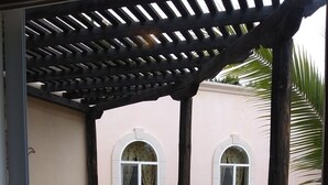A covered outdoor area with a curved balcony, two arched windows, and a tiled floor. - Casita El Sol, Pool View. (Loreto)