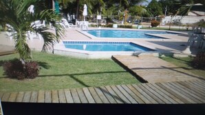 Ein Poolbereich mit zwei rechteckigen Pools, umgeben von Palmen und einer Holzterrasse.