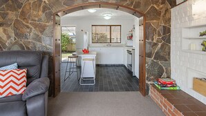 A modern kitchen with stone walls, a dining area with a grey sofa, and a small bar area.