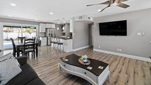 A modern living room with a dark brown coffee table, a gray sofa, and a dining area with a white table and chairs.