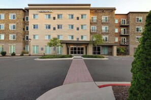 A multi-story hotel with a brick facade, a central entrance, and a landscaped driveway.