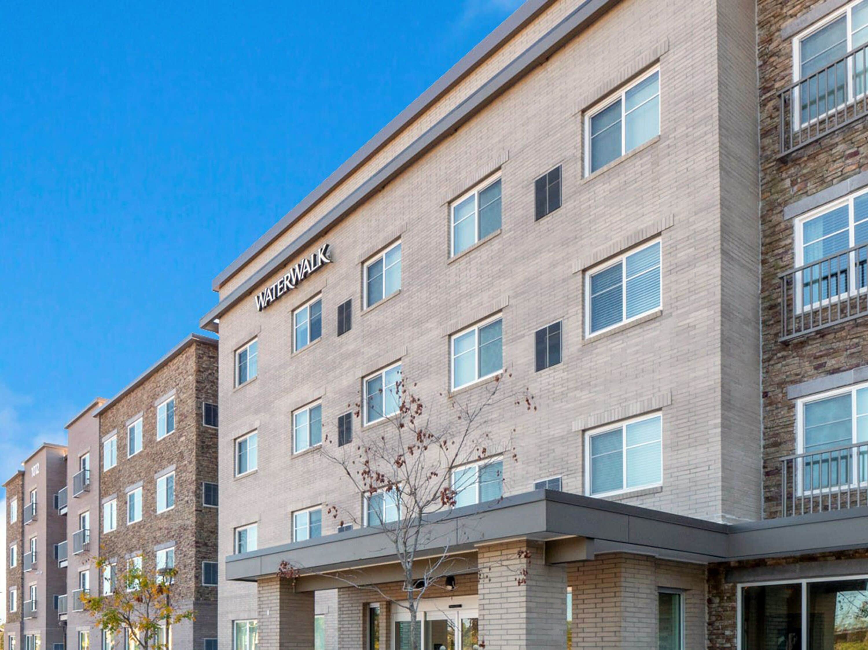 A multi-story building with the name "Waterwalk" on the facade, featuring a modern architectural style with a mix of brick and stone materials.