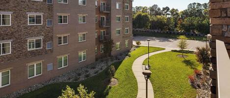 A multi-story building with a stone facade, a parking lot, and a well-maintained lawn.