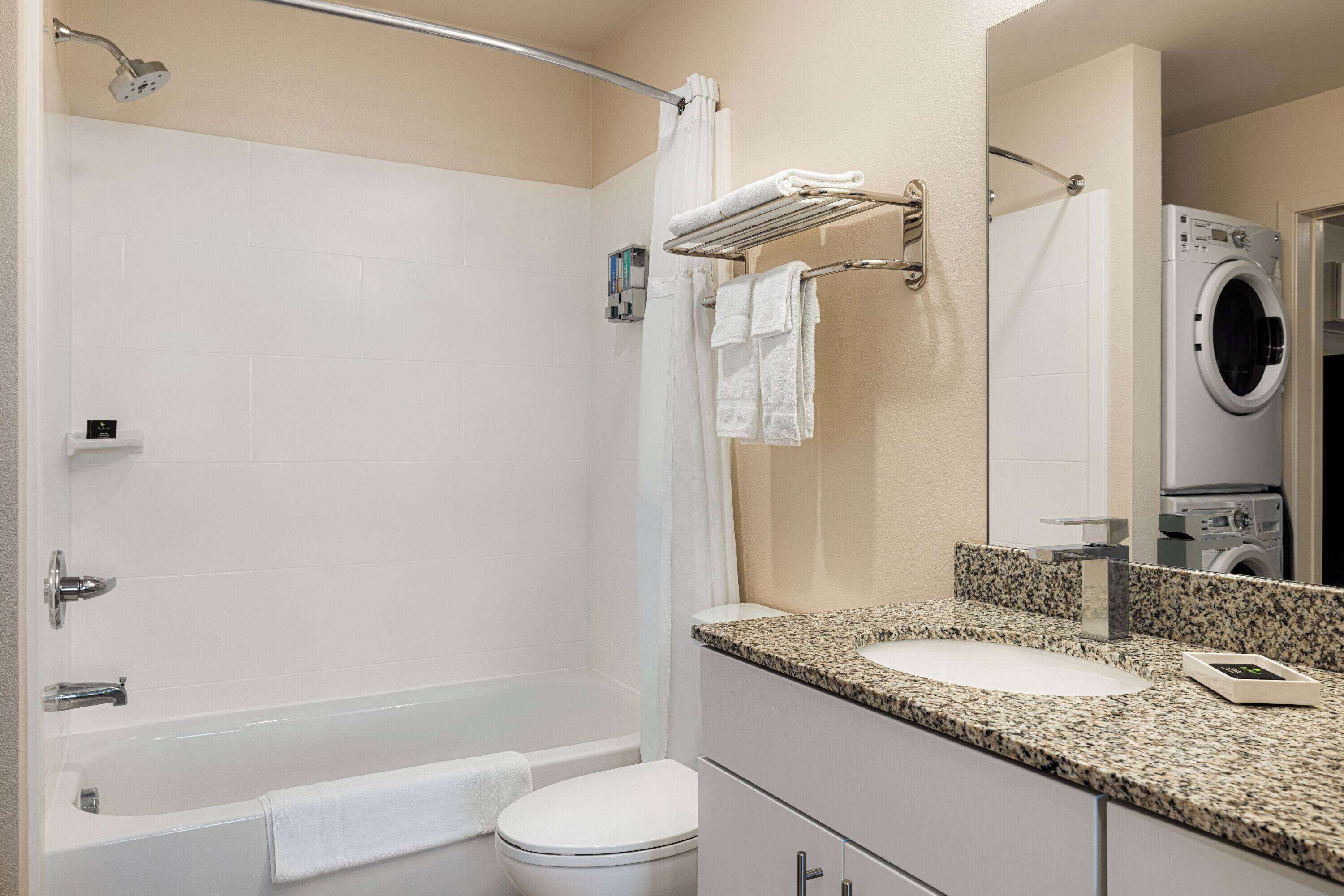 A bathroom with a bathtub, toilet, sink, and a washing machine.