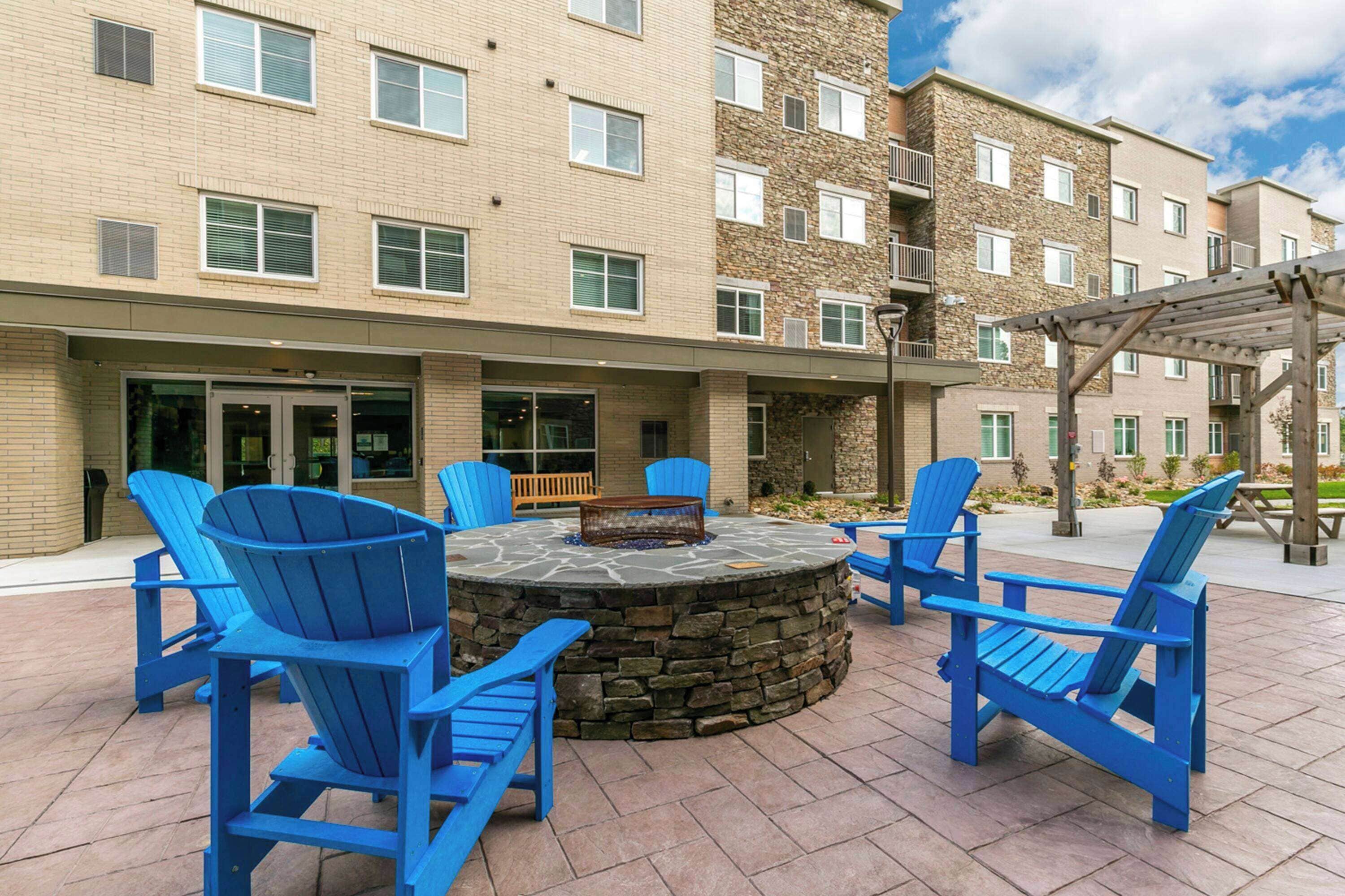 Un espace extérieur aménagé avec des chaises Adirondack bleues et un foyer en pierre.
