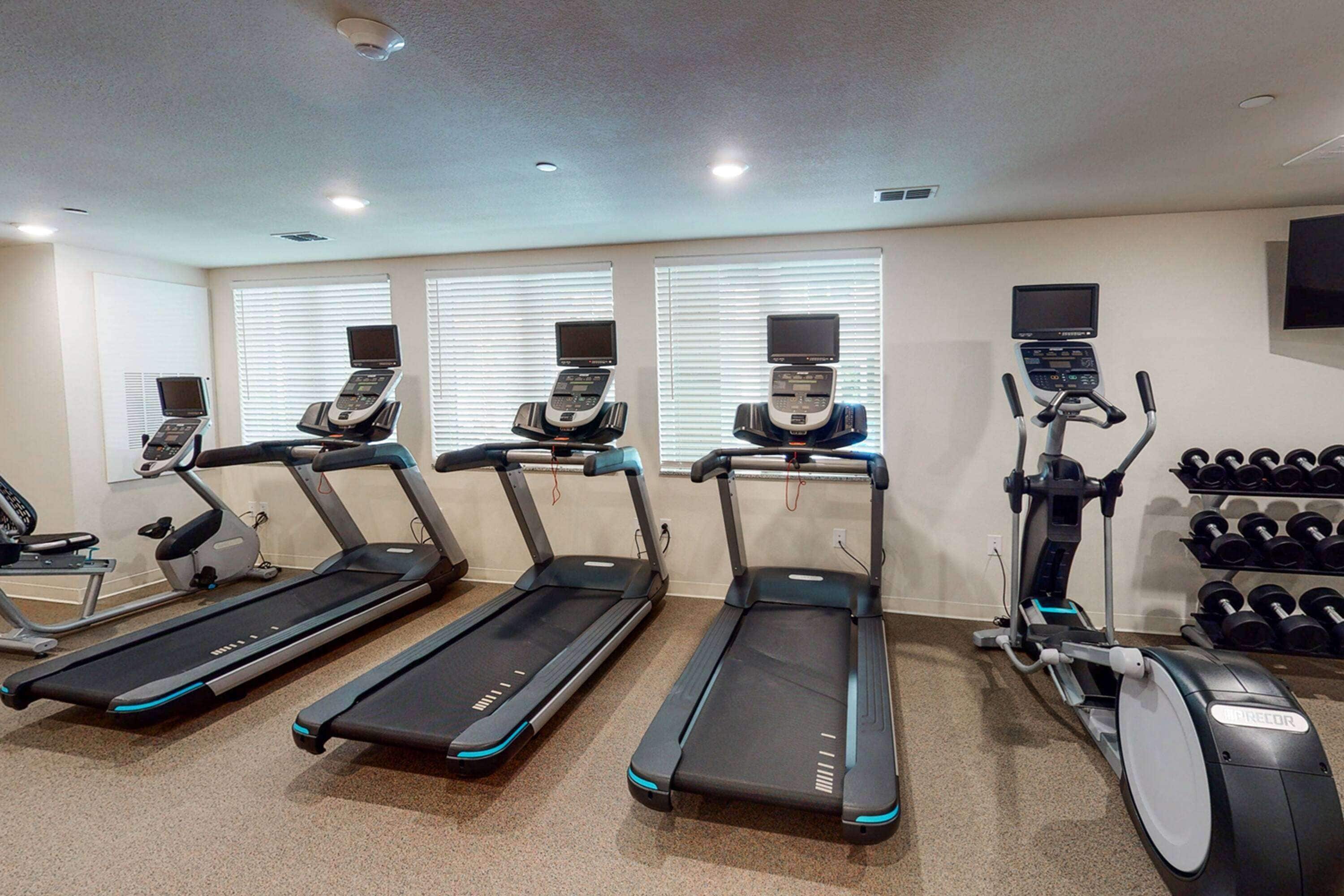A gym with treadmills, a stationary bike, and dumbbells.