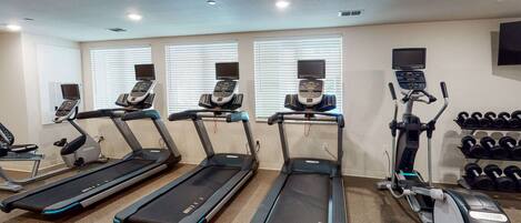 A gym with treadmills, a stationary bike, and dumbbells.