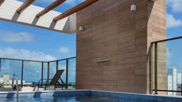 Une piscine sur le toit, avec une eau d’un bleu cristallin, une terrasse en bois et une vue sur la ville.