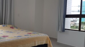 Une chambre avec un lit, de grandes fenêtres et des rideaux.