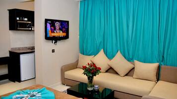 A living room with a sofa, a coffee table, and a television displaying a news program.