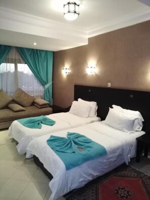Una habitación de hotel con dos camas, un sofá, una araña y apliques de pared.
