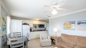 Un espacio habitable compacto con comedor, kitchenette, ventilador de techo y obras de arte en las paredes.