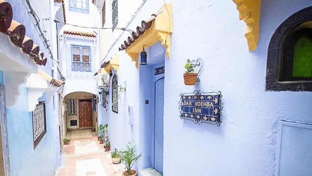 Une ruelle étroite avec un bâtiment bleu sur lequel on peut voir une enseigne indiquant « PAR NOKHRA INN ».