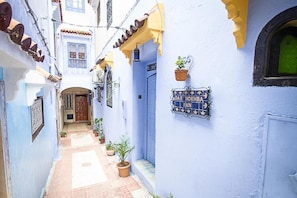 A narrow alleyway with a blue building featuring a sign for 'PAR NOKHRA INN'. - Dar Nokhba Inn (Chefchaouen)