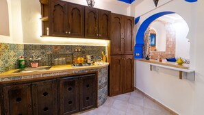 Une cuisine avec un mur recouvert de carreaux, des meubles en bois et un arc en bleu.