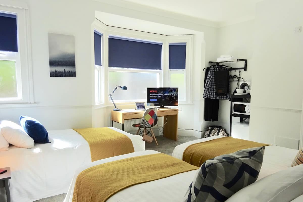 A hotel room with two beds, a desk with a computer, a chair, and a TV.