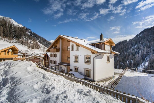 A snow-covered mountain lodge with a wooden exterior and multiple windows. - Steinbock Apartments (Samnaun)