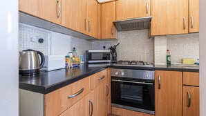Una cocina con armarios de madera, un microondas, una tetera y un tostador.