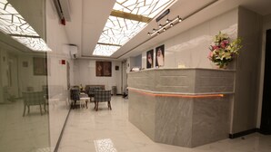 A reception area with a marble counter, glass walls, and a ceiling with a geometric pattern. - Lahdat Hotel Al Balad (Jeddah)