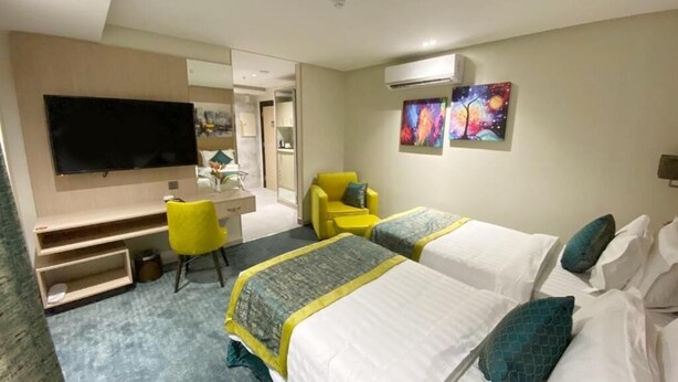 A hotel room with two beds, a desk, a chair, and a TV. - Lahdat Hotel Al Balad (Jeddah)