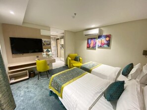 A hotel room with two beds, a desk, a chair, and a TV. - Lahdat Hotel Al Balad (Jeddah)