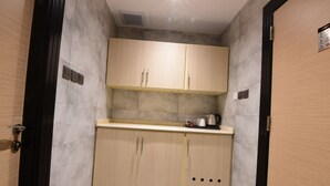 A compact kitchen with two cabinets, a countertop, and a kettle. - Lahdat Hotel Al Balad (Jeddah)